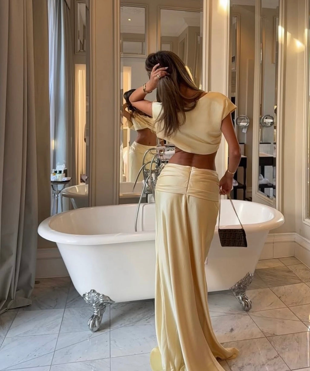 Woman in a beige outfit standing in a bathroom with a freestanding bathtub.