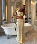 Woman in a beige outfit standing in a bathroom with a freestanding bathtub.