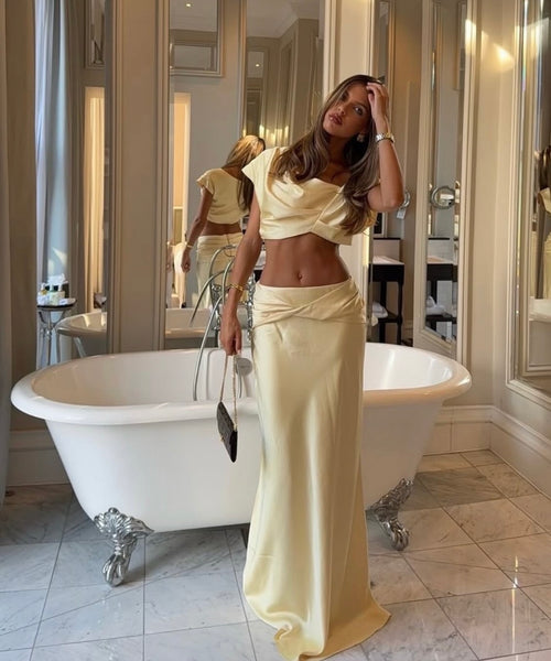 Woman in a beige outfit standing in a bathroom with a freestanding bathtub.