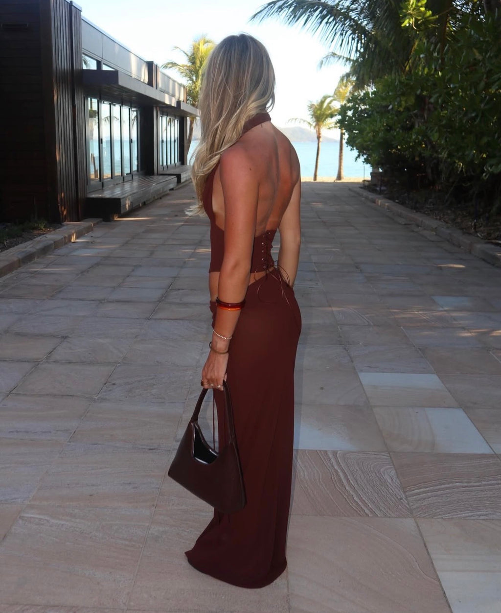 Woman in a brown dress walking on a stone path with a scenic background
