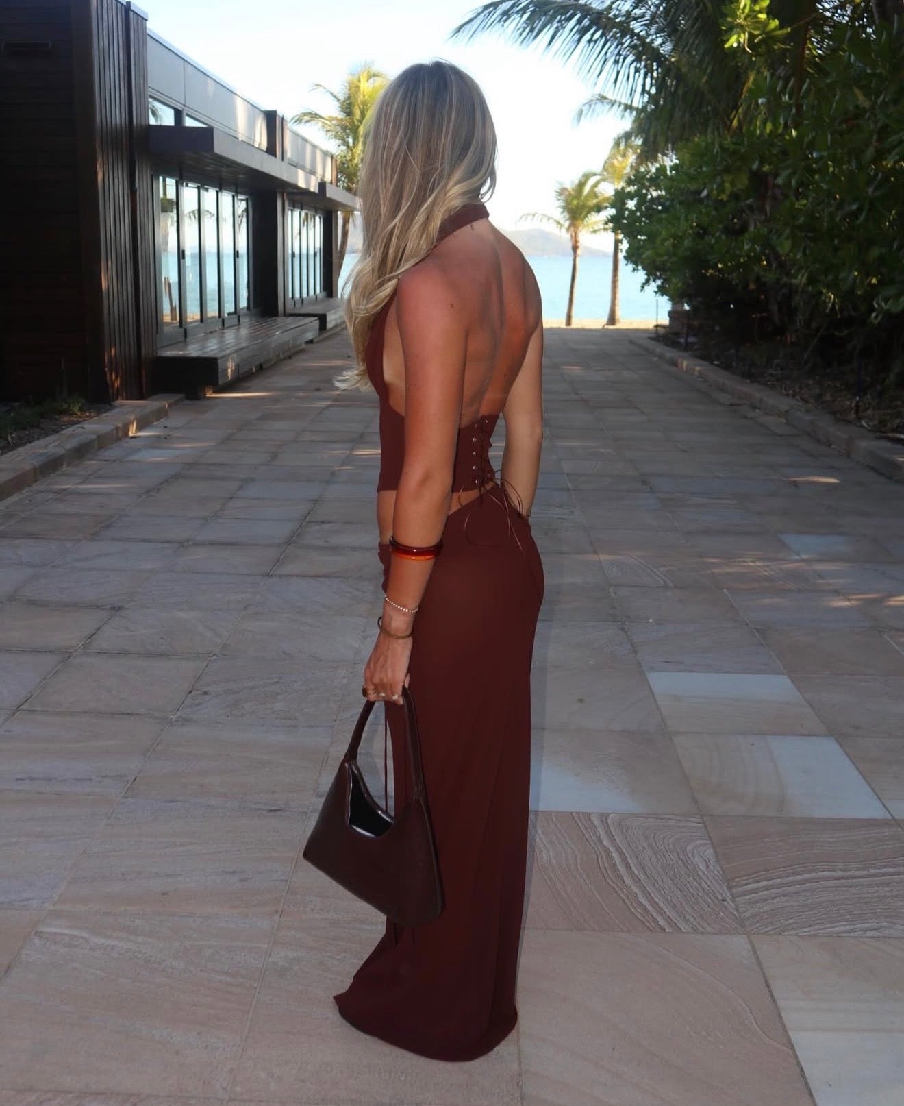 Woman in a brown dress walking on a stone path with a scenic background