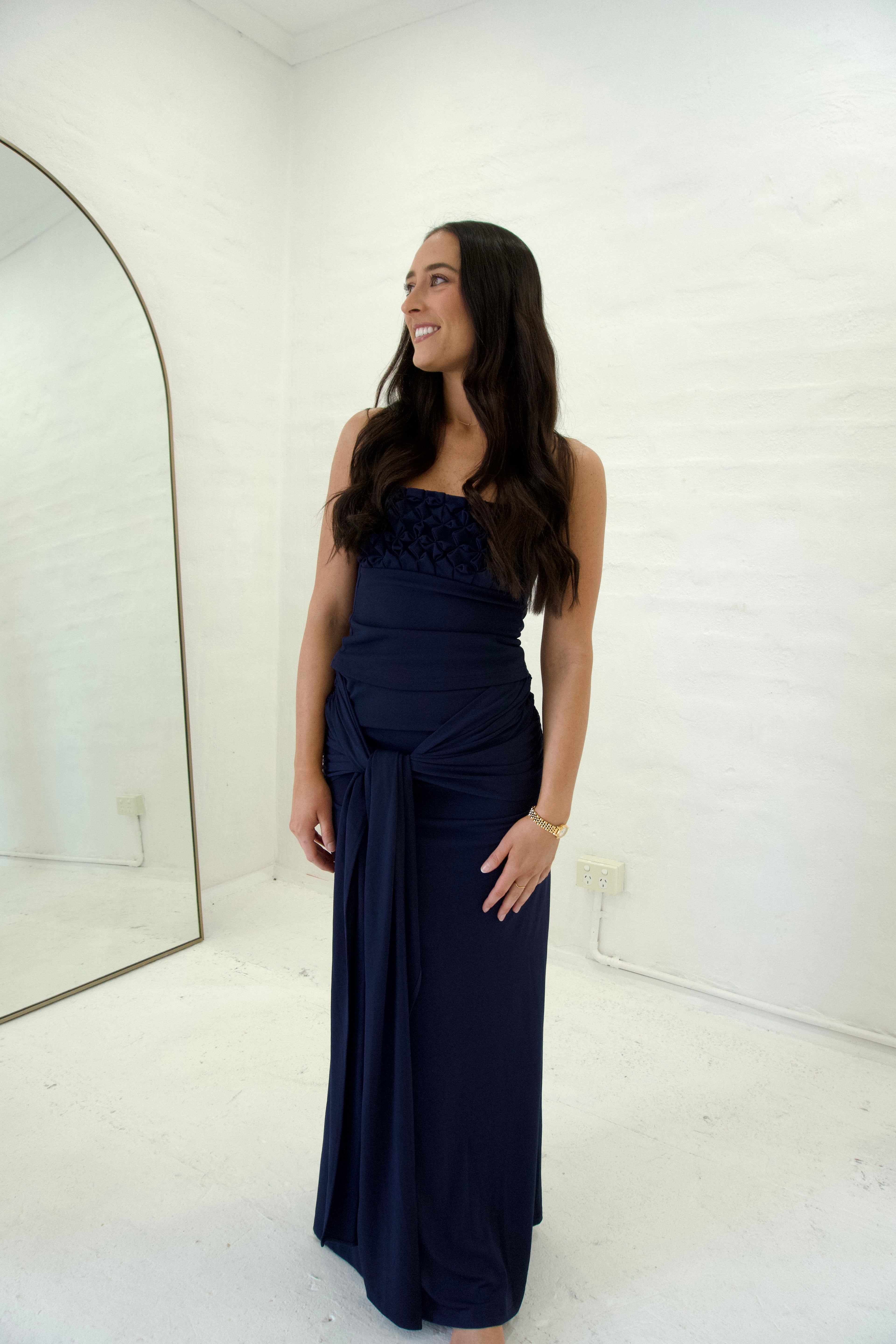 Woman wearing a navy blue set in a room with a mirror.