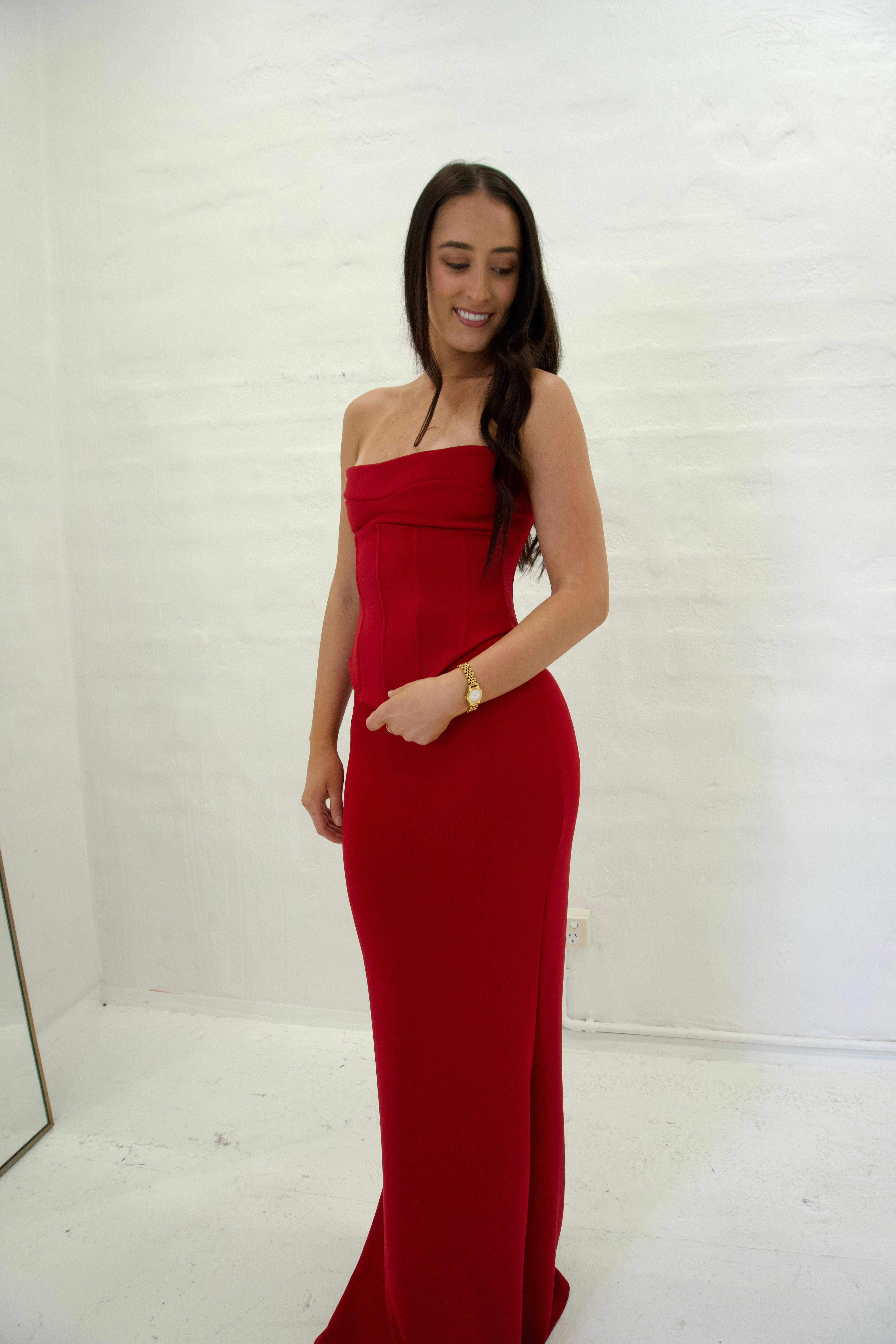 Woman wearing a red strapless gown against a white background