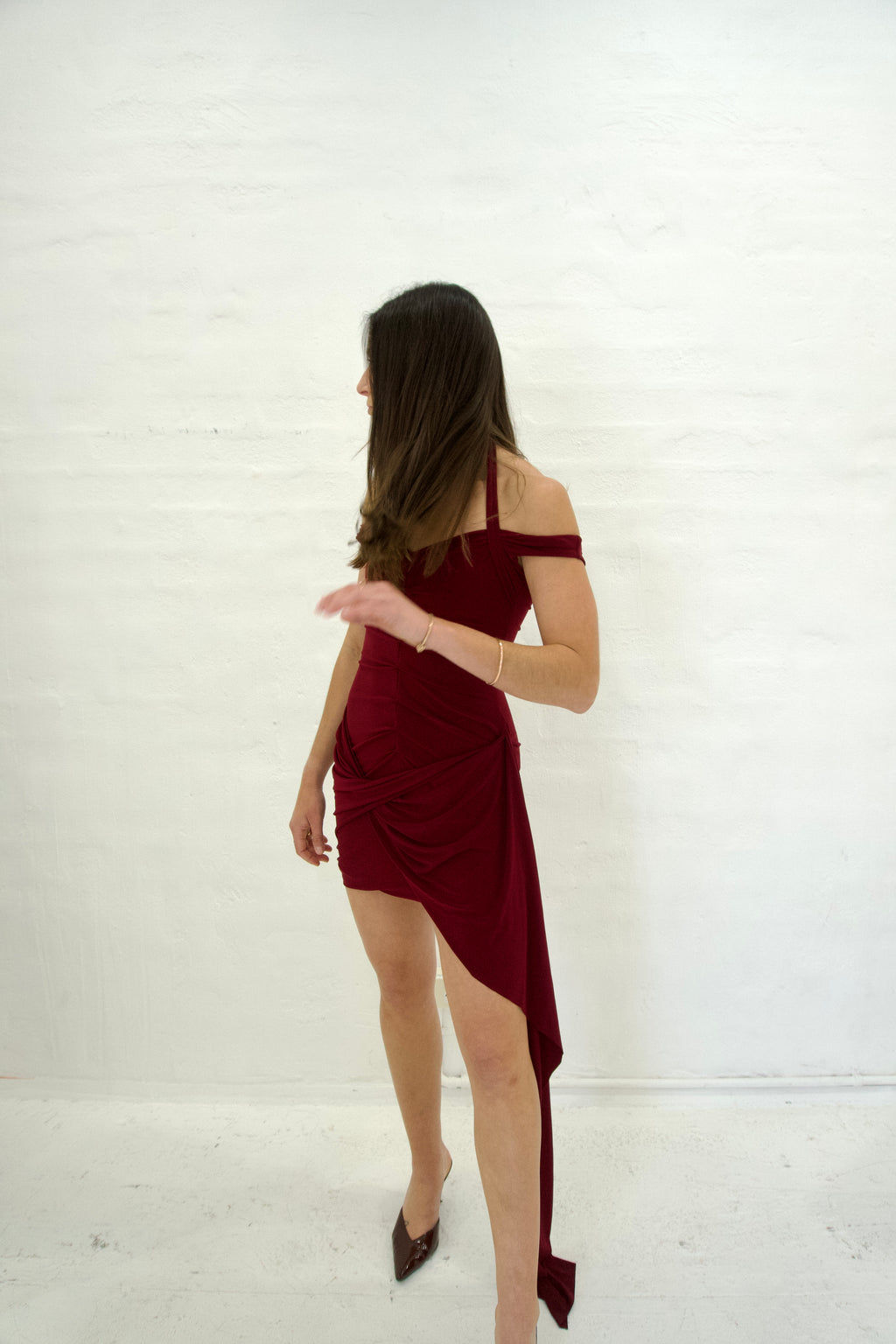 Woman wearing a burgundy off-shoulder dress against a white background