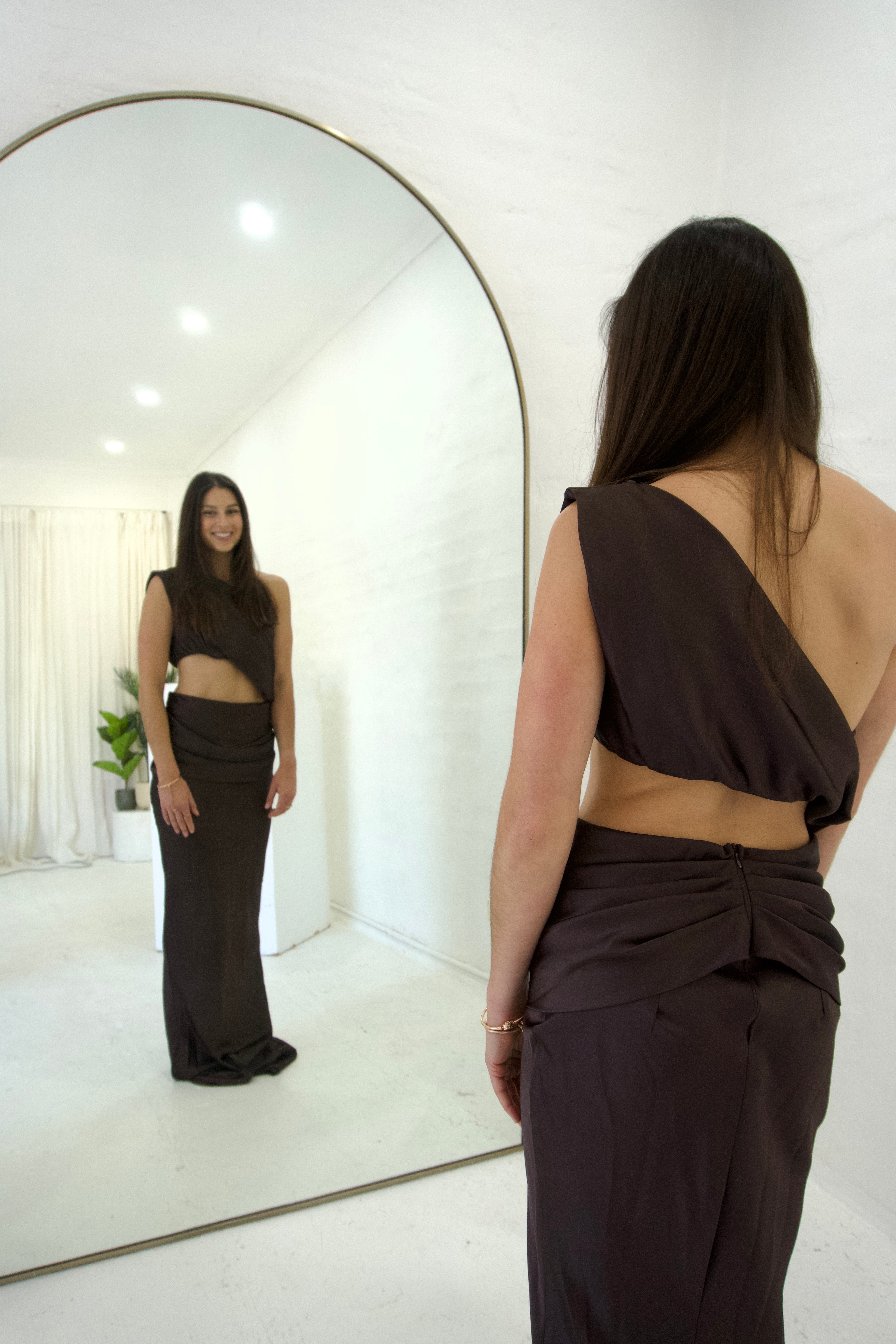 woman looking at herself in the mirror in a brown dress 