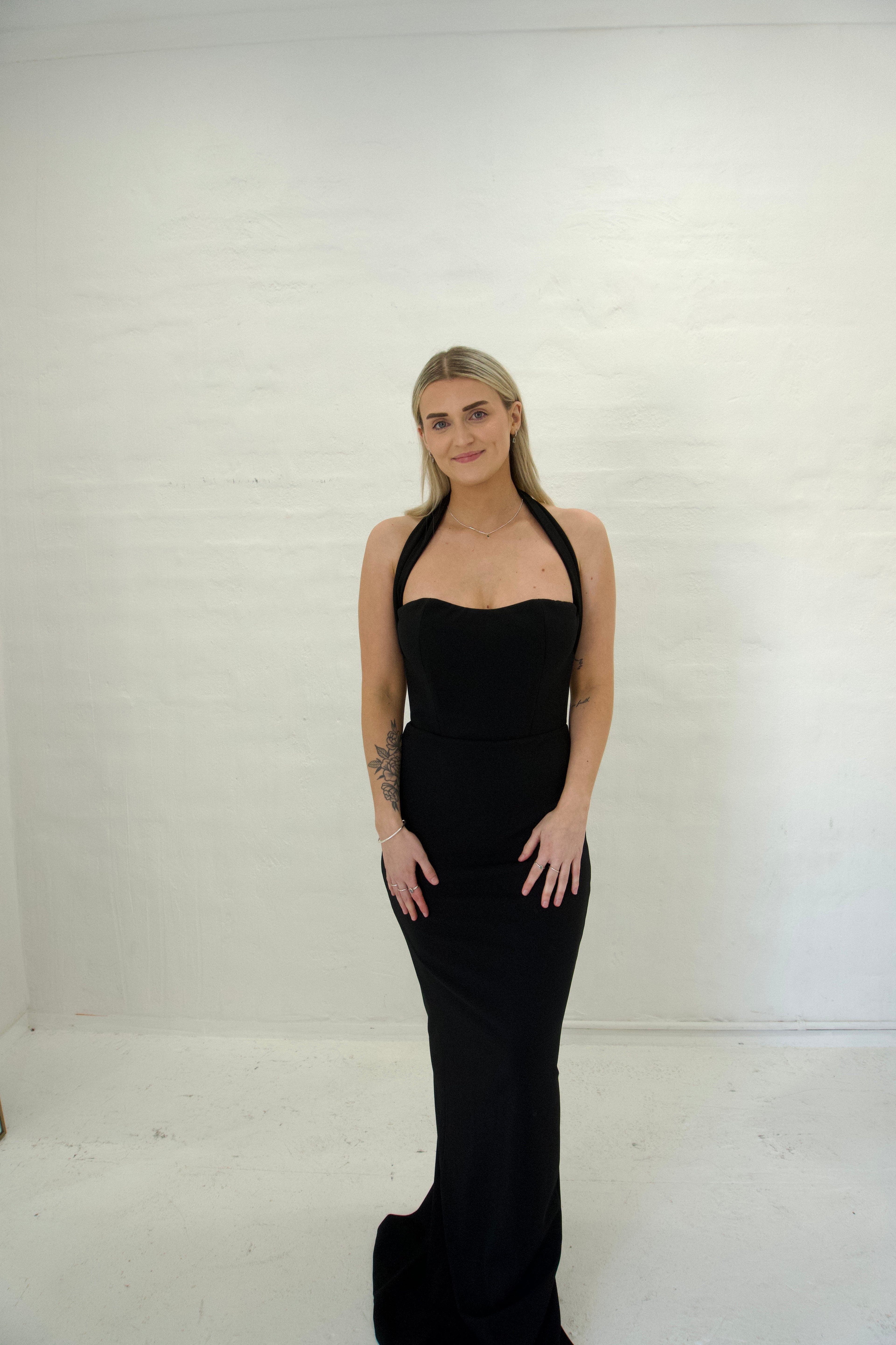 Woman wearing a black halter neck dress against a white background