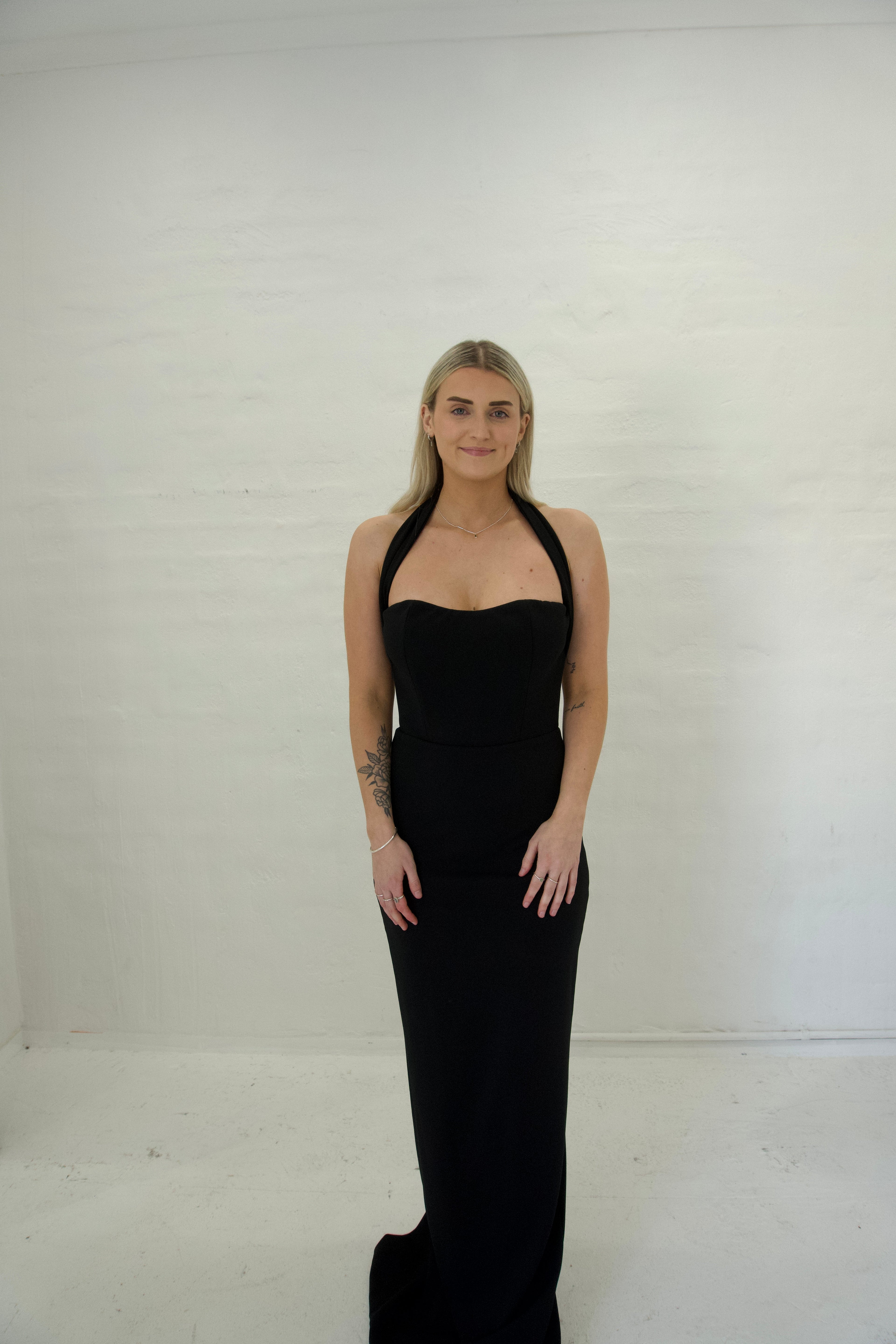 Woman wearing a black halter neck dress against a white background