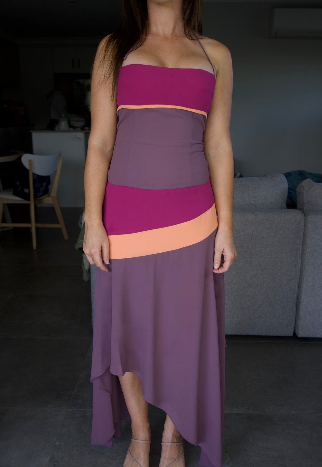 Person wearing a two-tone dress with a gradient from purple to pink in a room.