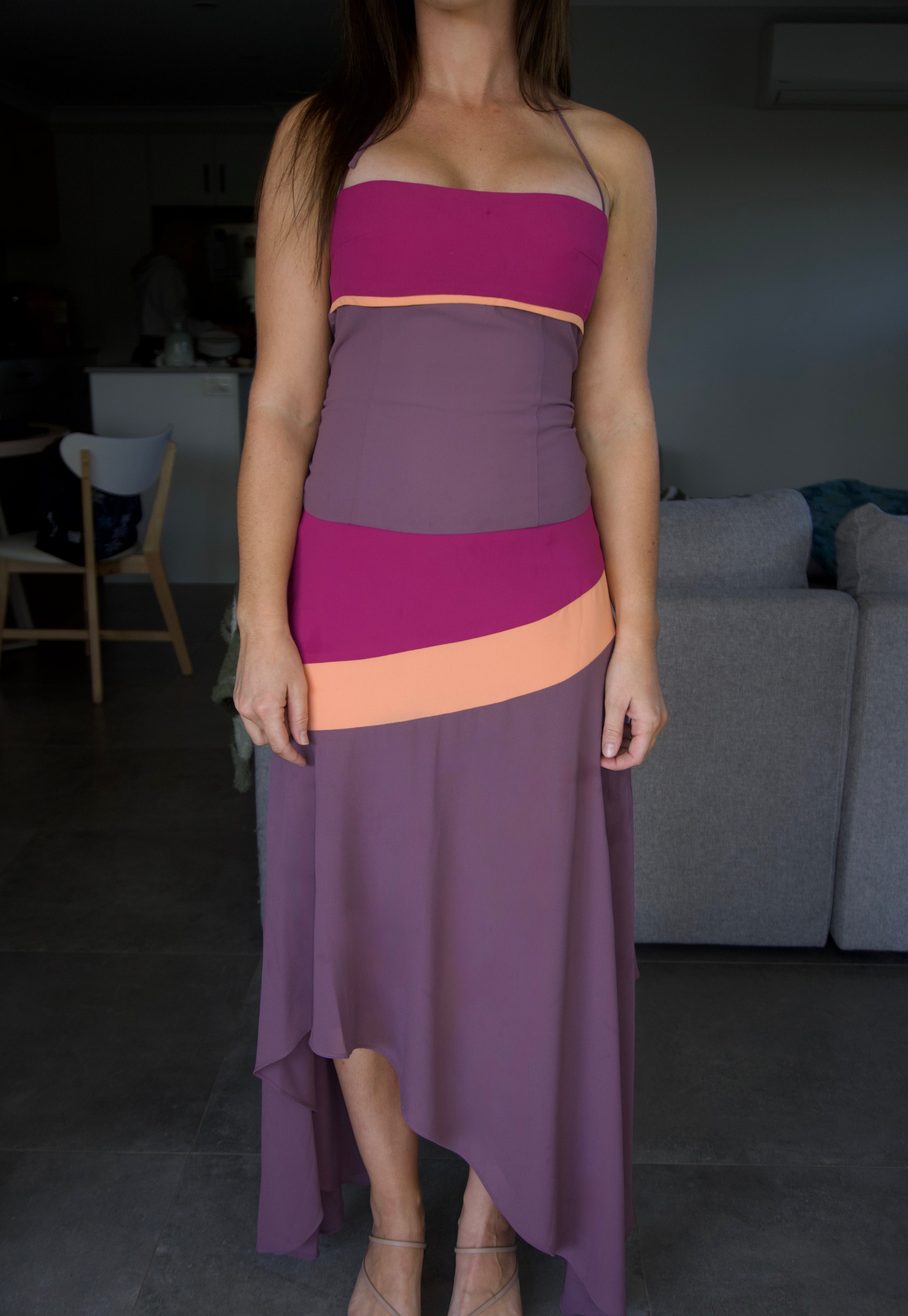 Person wearing a two-tone dress with a gradient from purple to pink in a room.