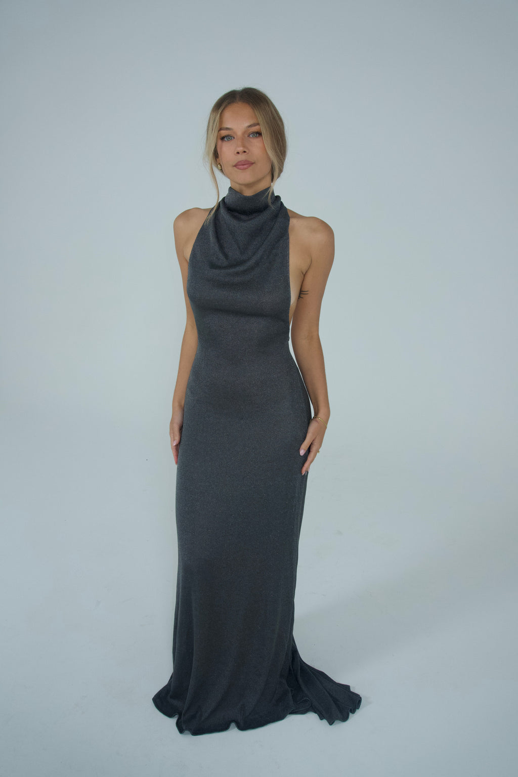Women wearing a metallic turtle neck gown in front of a white backdrop. 