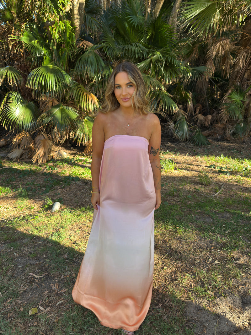 Woman wearing a pink strapless dress standing in a natural setting with palm trees. - @chloecid