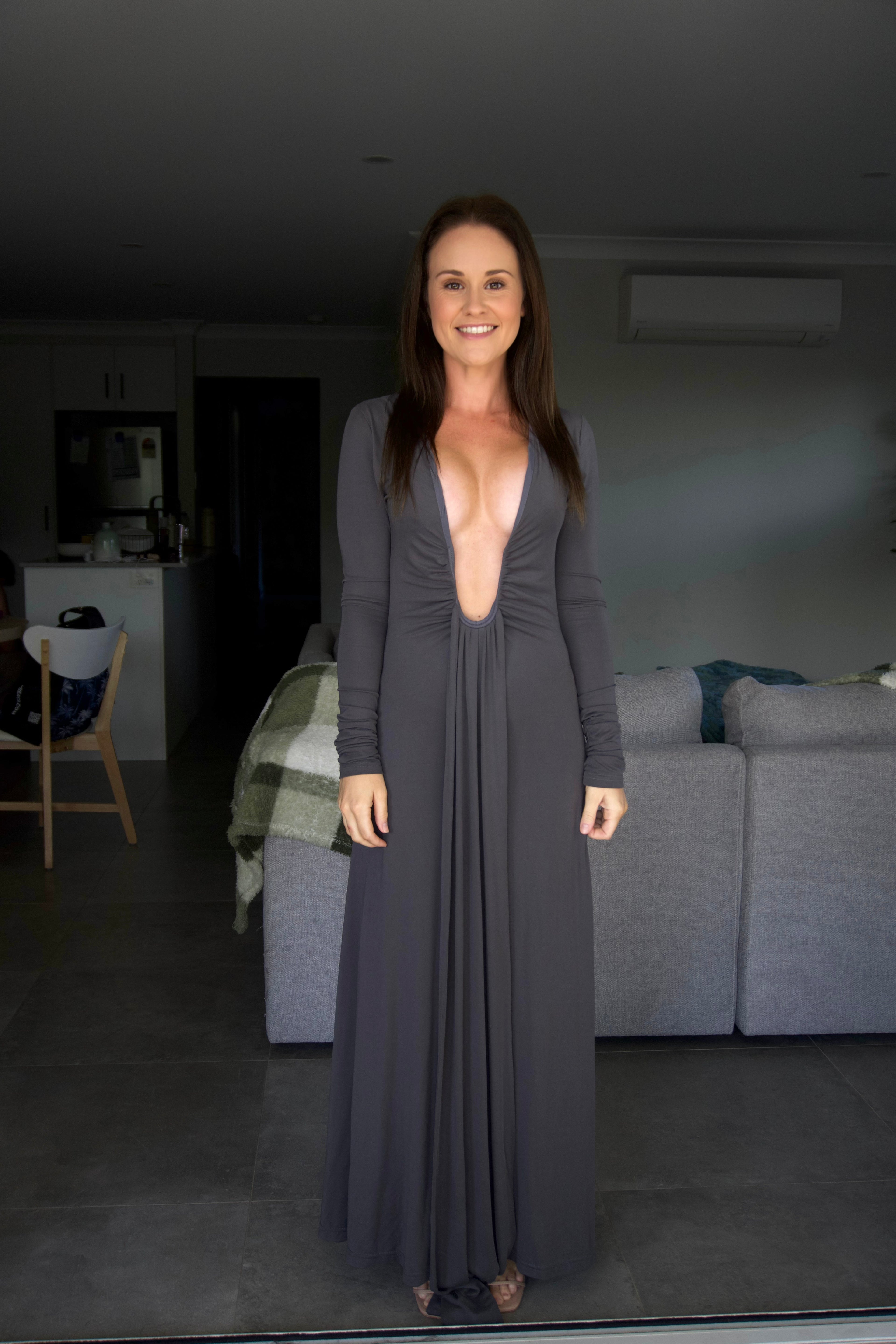 Woman wearing a long, dark gray dress standing in a living room.