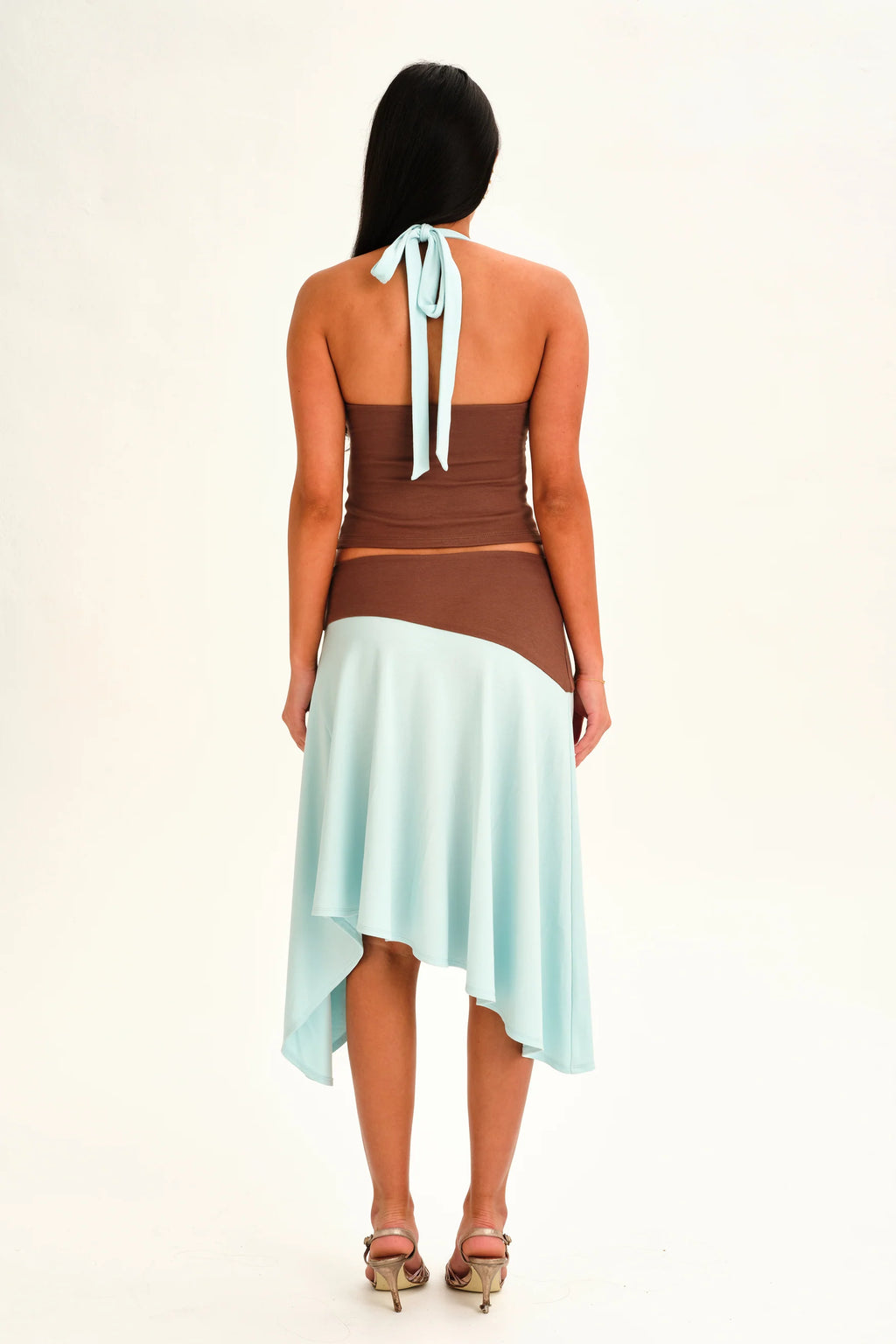Woman wearing a brown top and light blue skirt on a white background