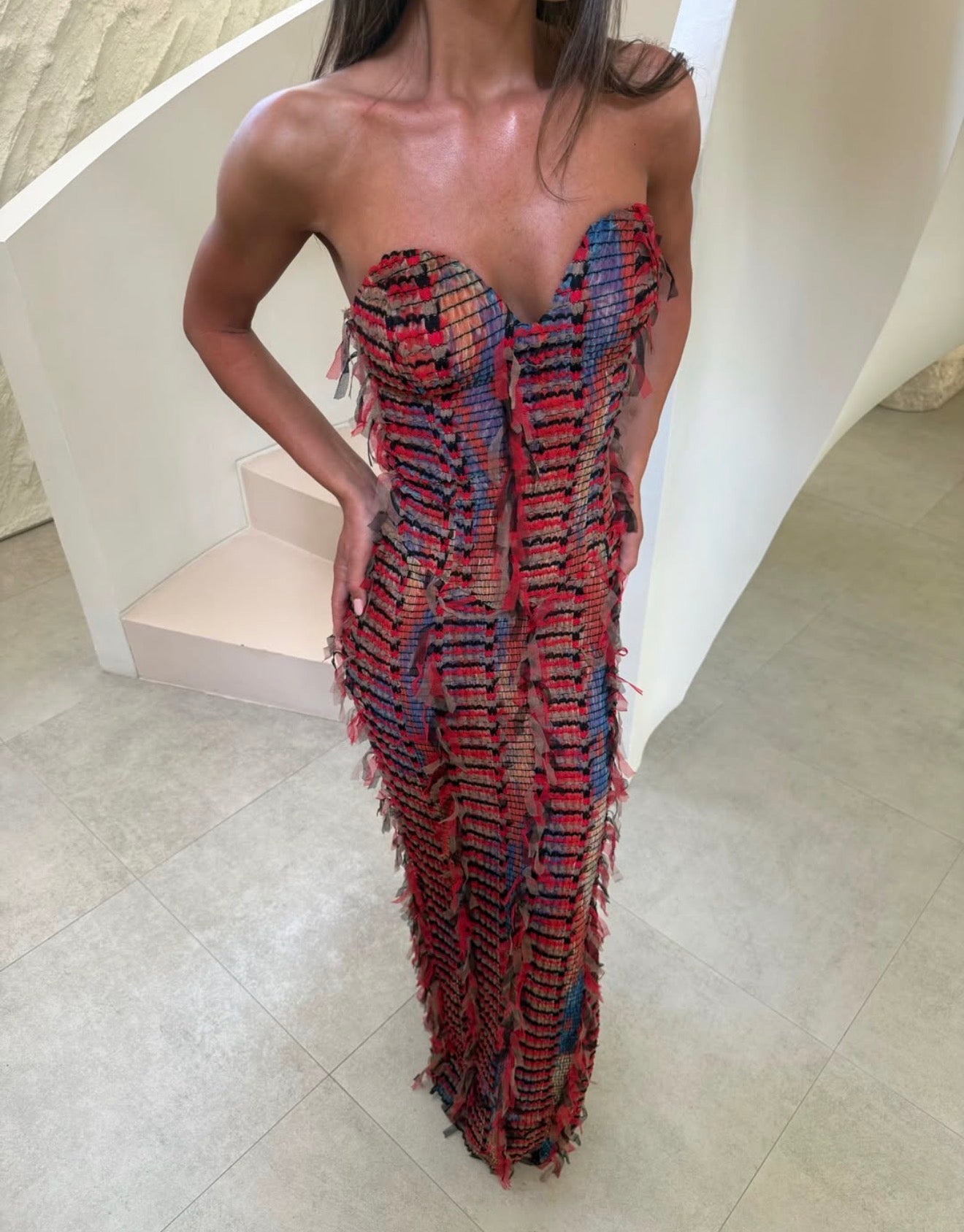 picture of a girl standing with her hands on hips in a beige background wearing a red maxi dress