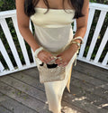 Woman holding a beaded handbag on a wooden deck with white railing.