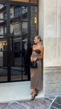 Woman in a stylish outfit standing outside a building entrance.