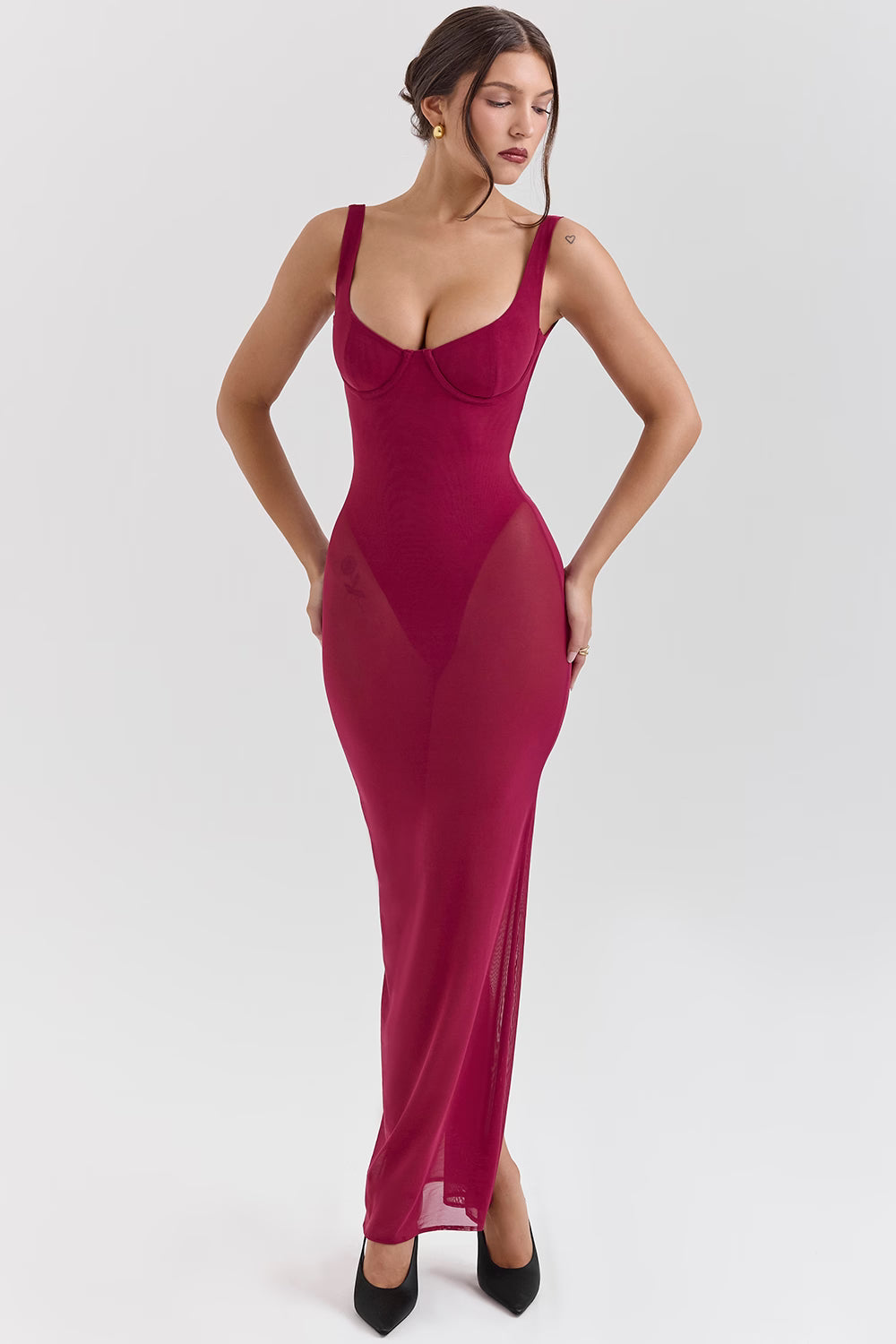 Woman wearing a magenta evening gown with sheer panels on a white background.