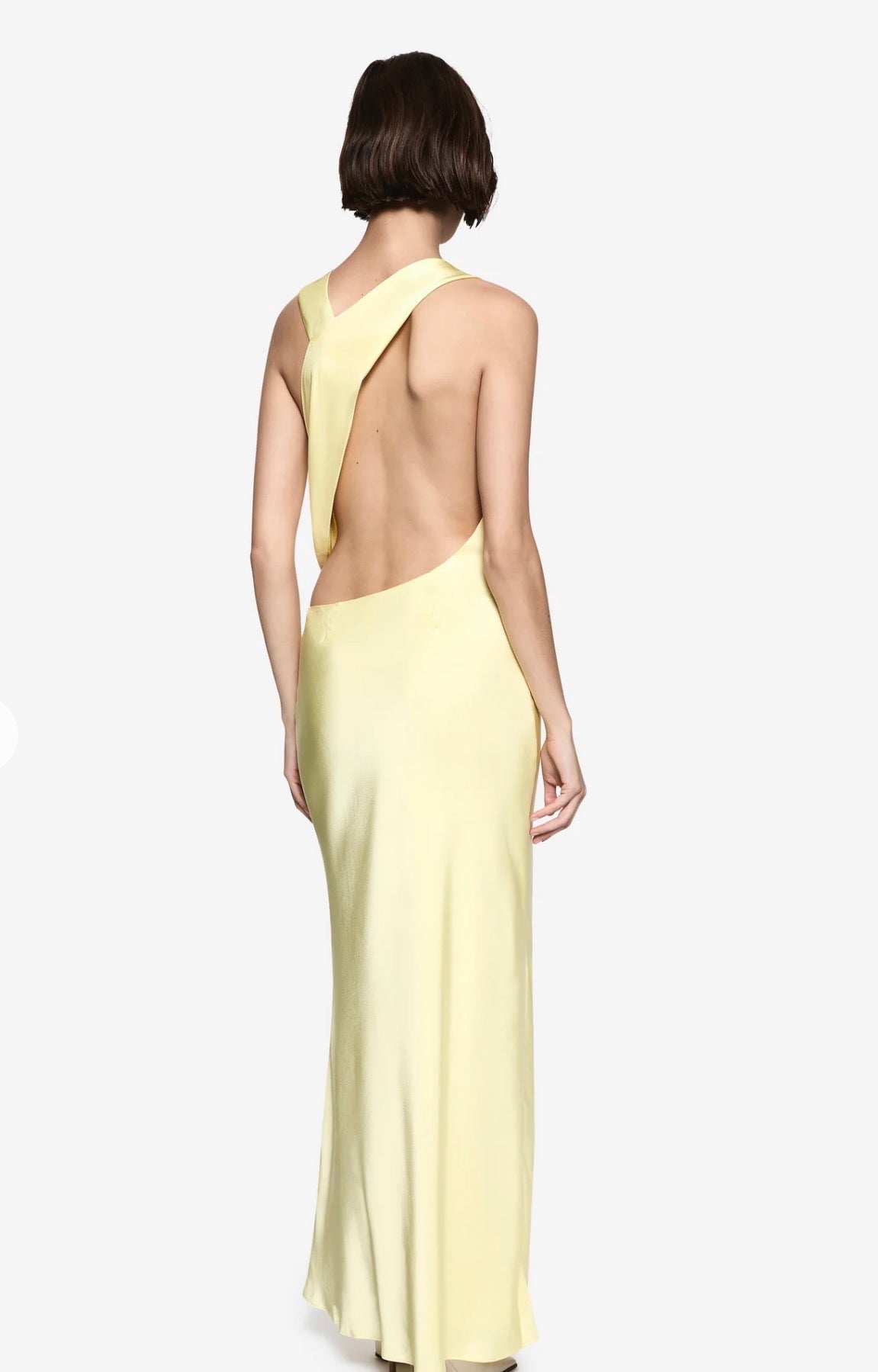 Women standing in front of a white backdrop in q yellow maxi satin dress.