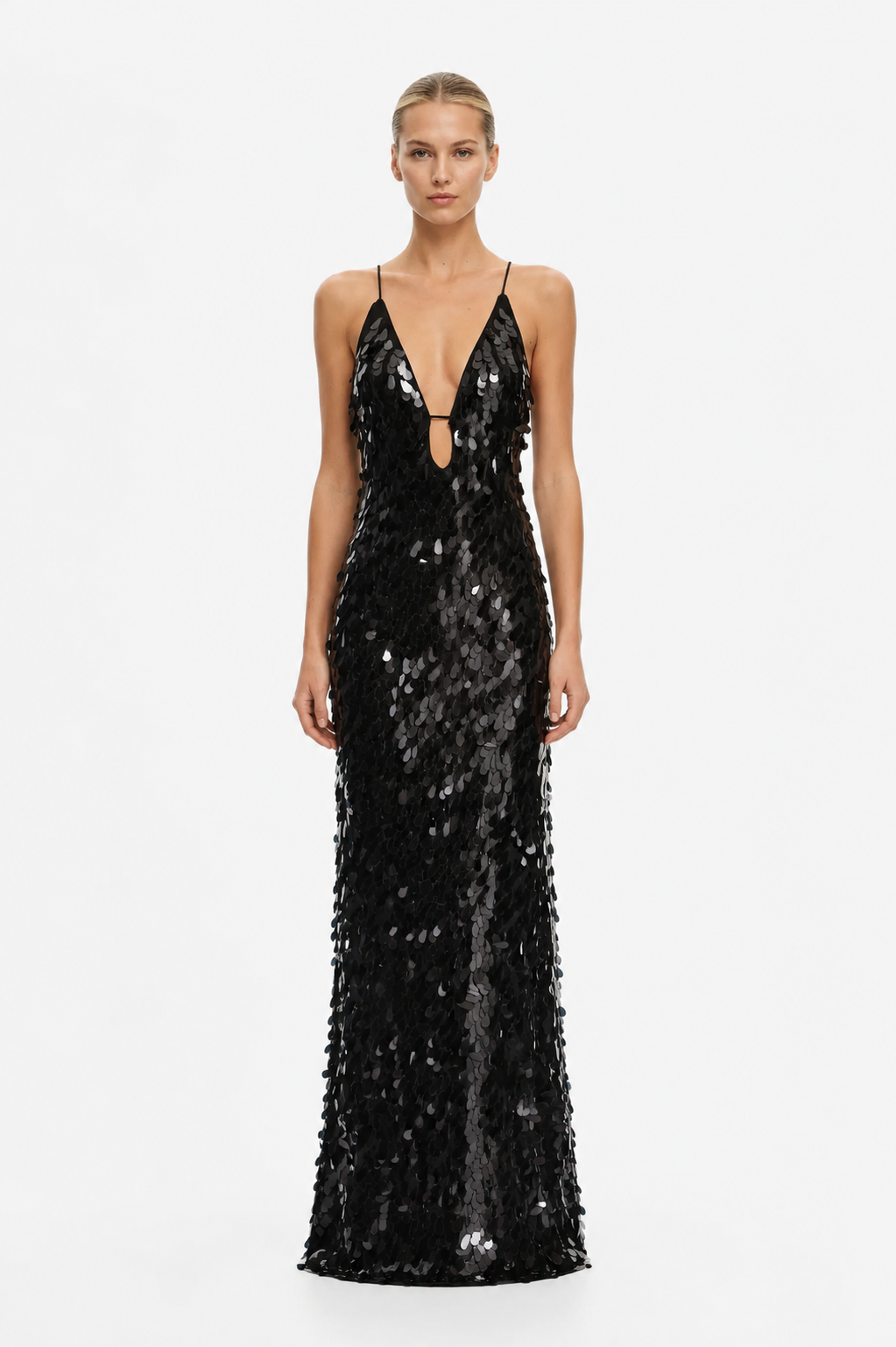 A model wearing a floor-length black sequined gown with thin straps, a plunging neckline with a small keyhole cutout, and a fitted silhouette, photographed against a plain light gray studio background.