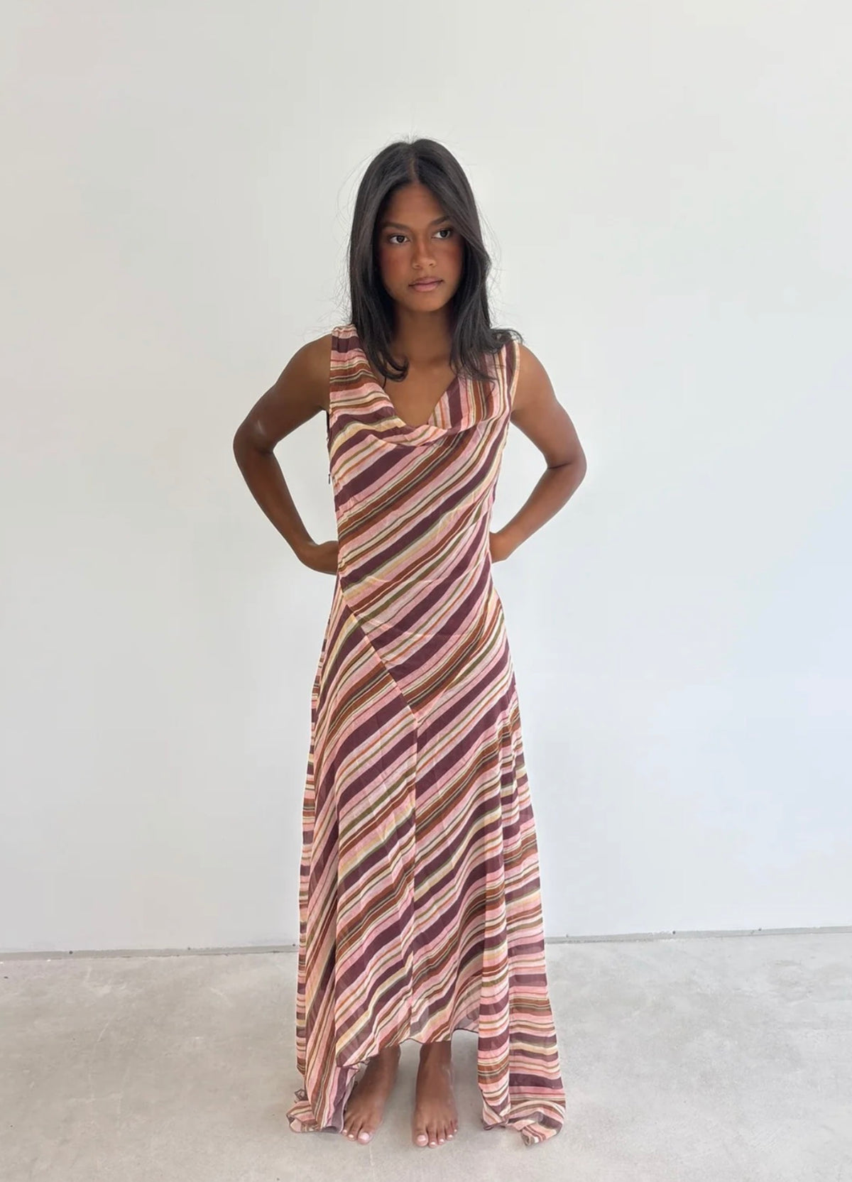 Girl wearing a pink striped dress in front of a white backdrop.