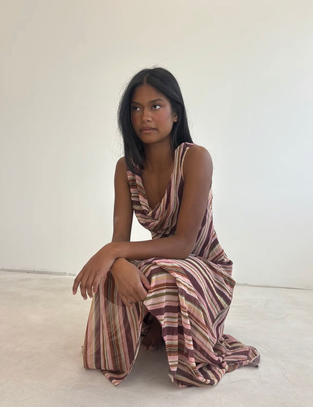 Girl wearing a pink striped dress in front of a white backdrop.