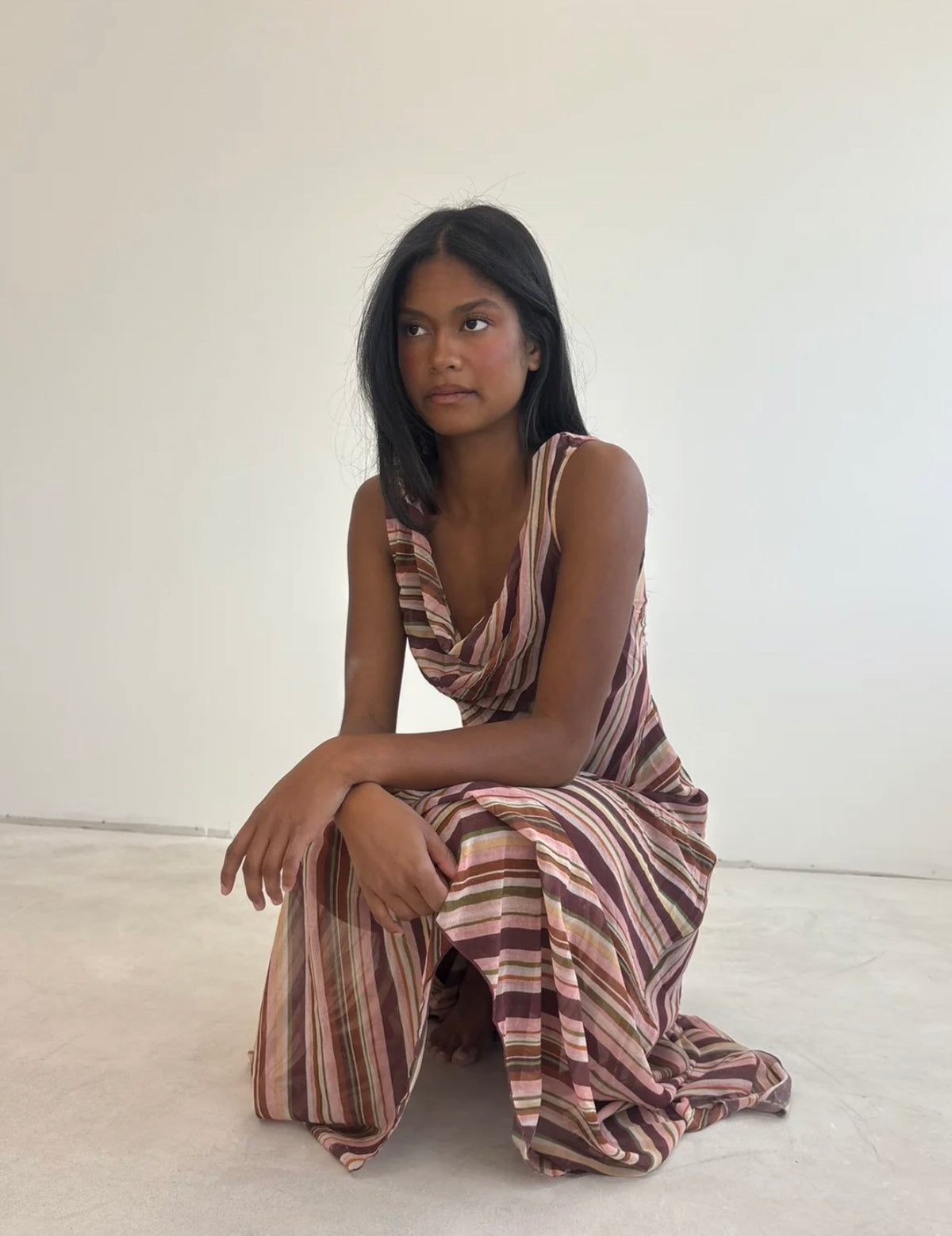 Girl wearing a pink striped dress in front of a white backdrop.