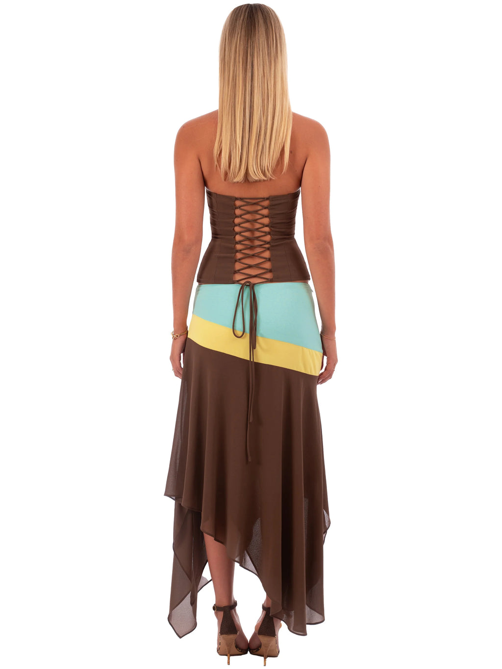 Woman wearing a colorful dress with a brown base and blue and yellow accents on a white background