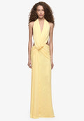  Model wearing a pale yellow halter neck maxi dress with a plunging neckline, draped waist detailing and floor-length silhouette.
