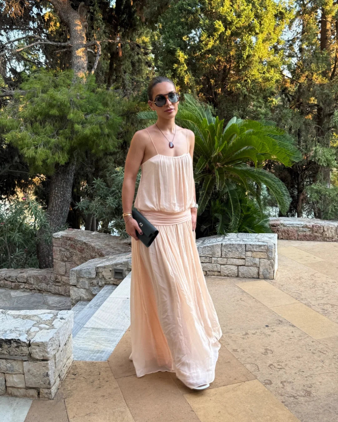 A woman wearing a light peach chiffon strapless maxi dress 