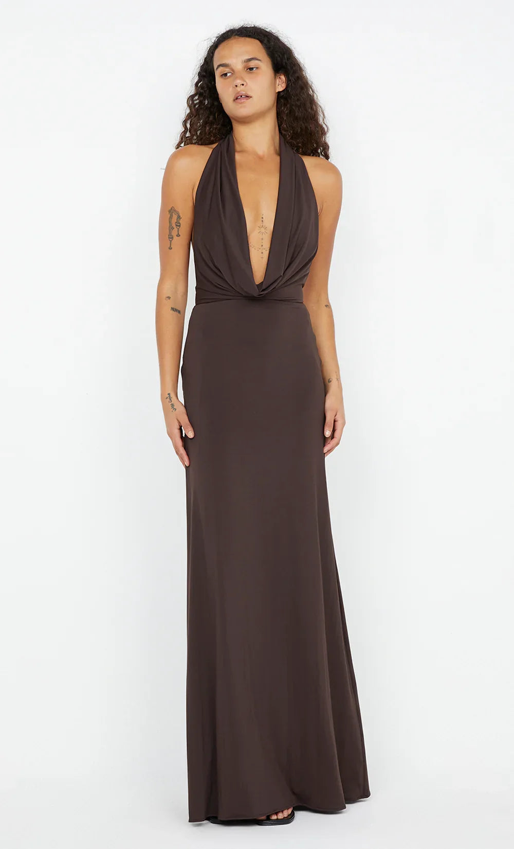 Woman wearing a black evening gown in a minimal white room.