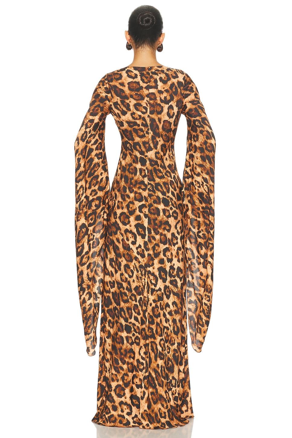  Back view of a model wearing the Helsa Roslind leopard print maxi dress, featuring a fitted floor-length silhouette, long sleeves and dramatic draped fabric overlays at the cuffs.
