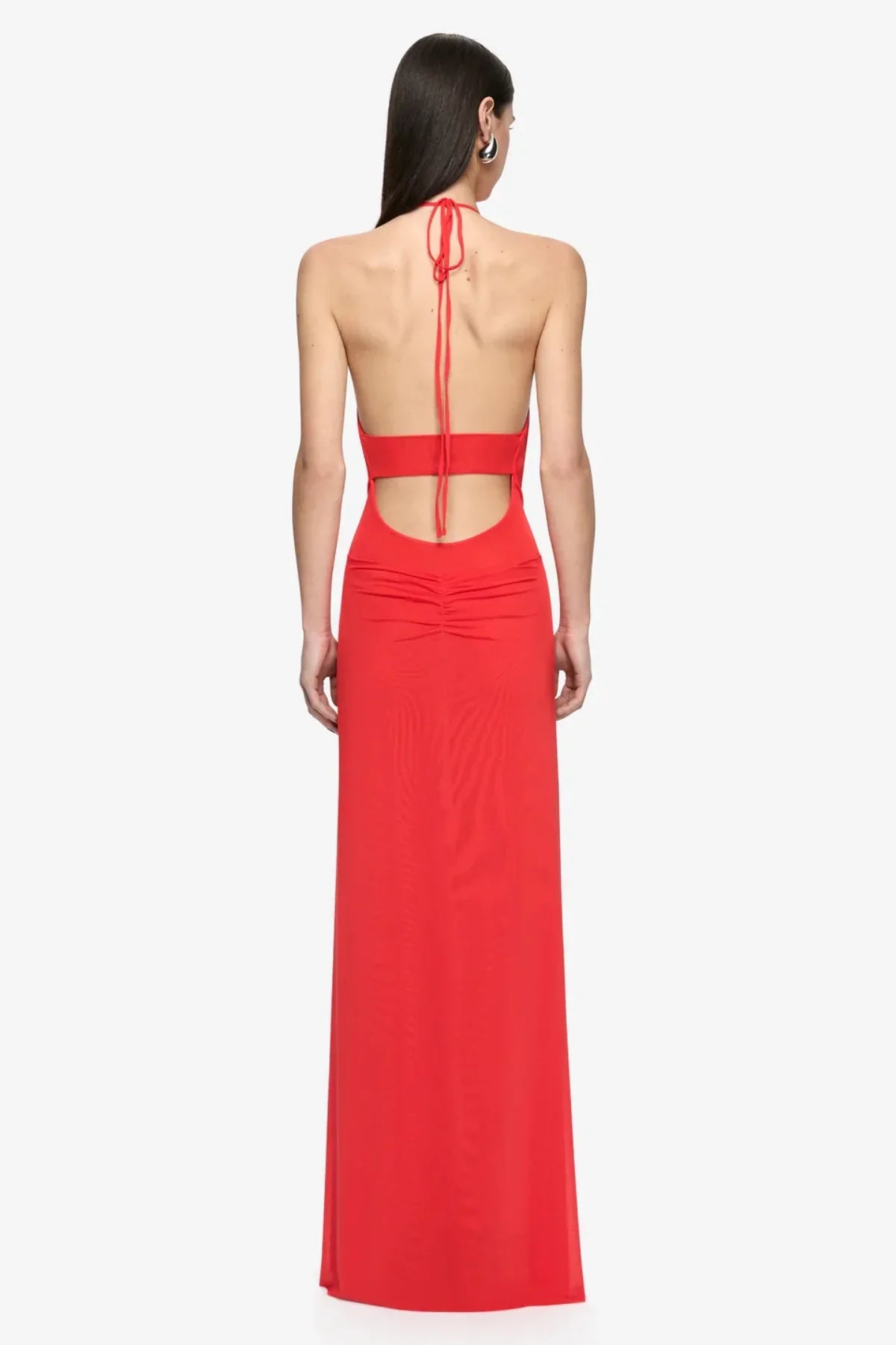 Back view of the Bec + Bridge Xanthi V Neck Maxi Dress in Flame, featuring an open back, adjustable halter neck ties, a cut-out waist and gathered detailing across the lower back, photographed against a white background.