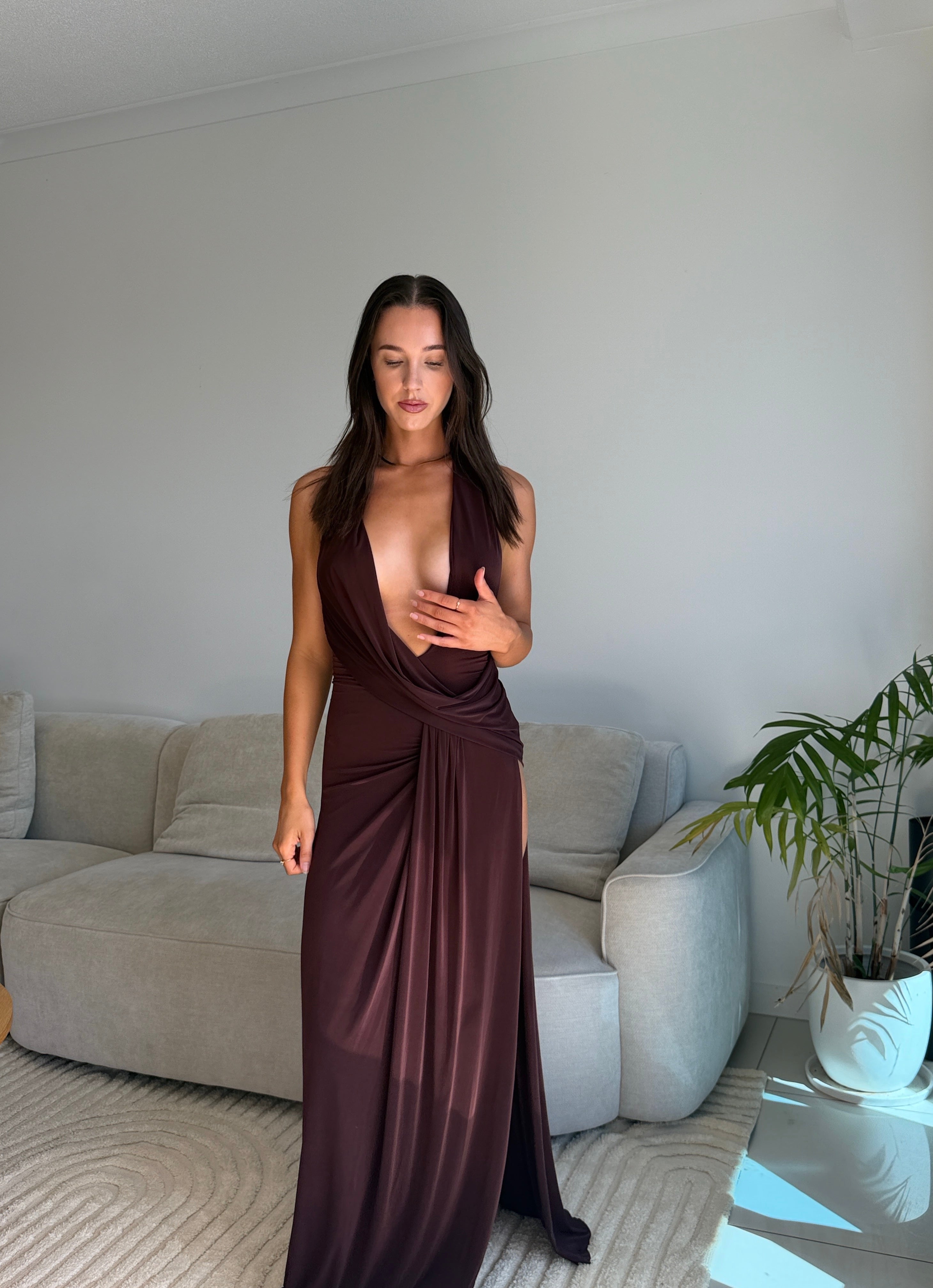 Woman in a brown dress standing in a living room.