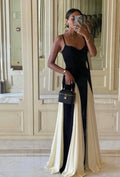 Woman in a black and white dress taking a mirror selfie in an elegant interior setting.
