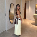 Woman in a white and brown dress standing in a modern interior setting. - @ashleywolfexx_
