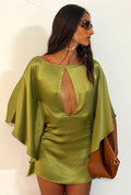 Woman wearing a green satin dress with a plunging neckline against a white background