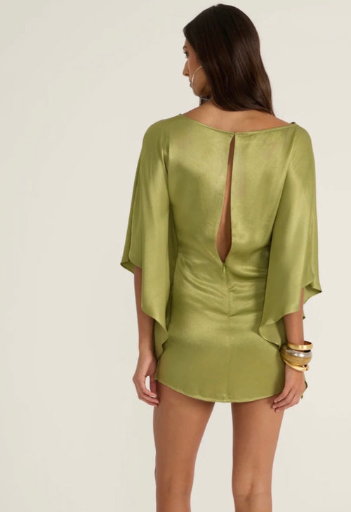 Woman wearing a green dress with a cut-out back on a white background