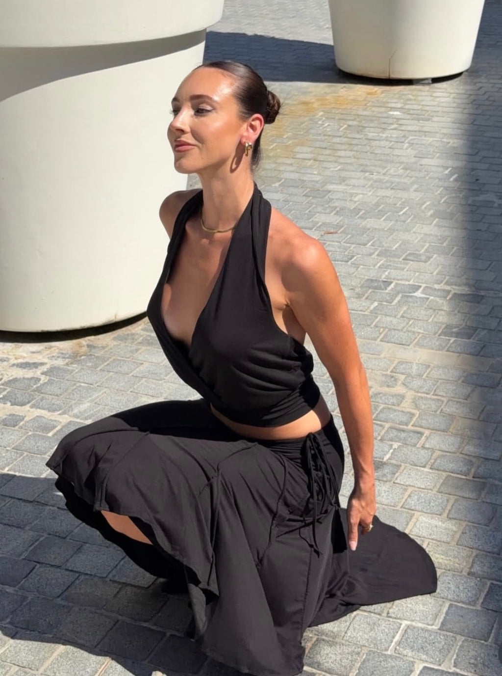 Woman in black outfit sitting on a stone pavement