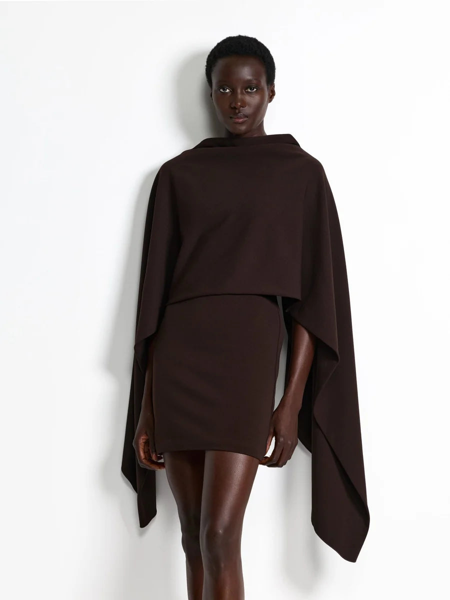 Model wearing the Effie Kats Kathryn Mini Dress in Coffee, featuring a high neckline, structured mini silhouette and oversized draped cape detailing, styled with brown pointed-toe heels against a white studio background.