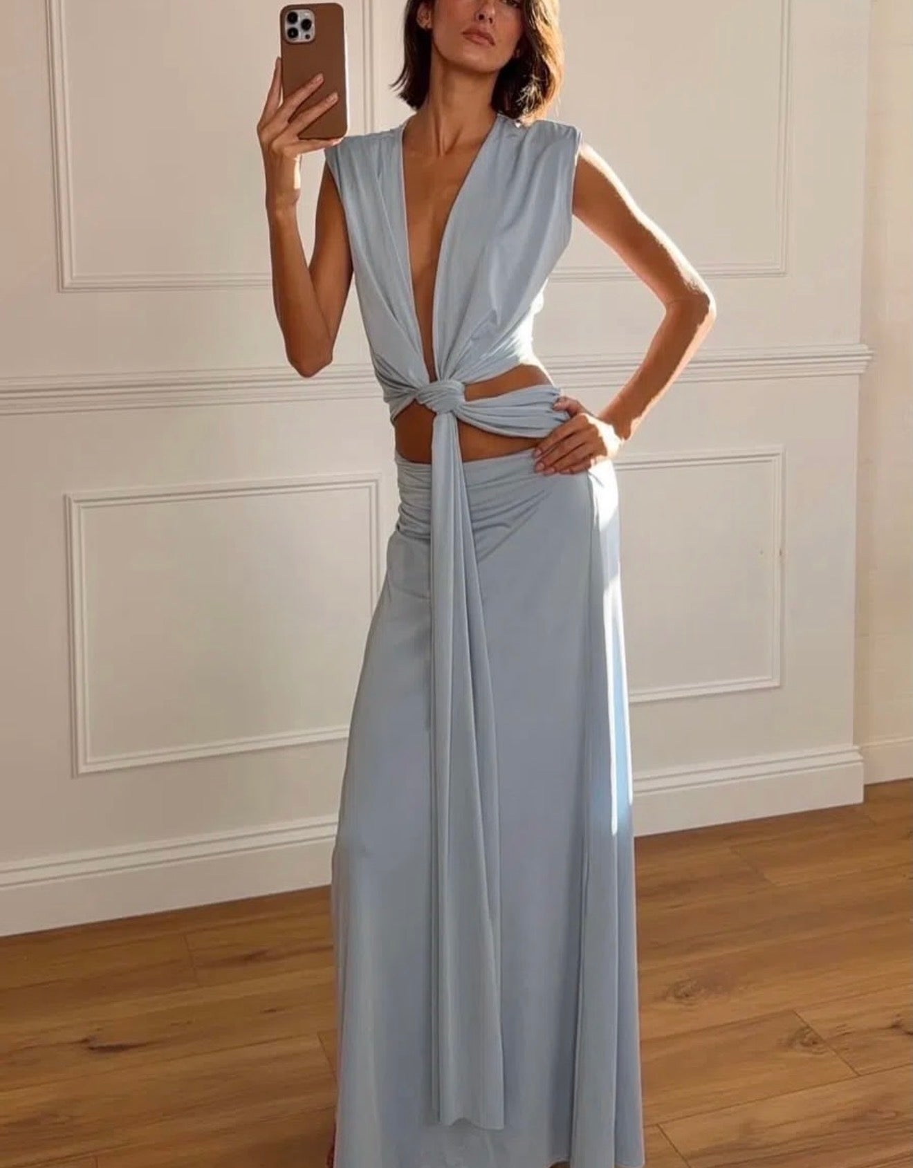 Woman wearing a light blue dress with a white wall background