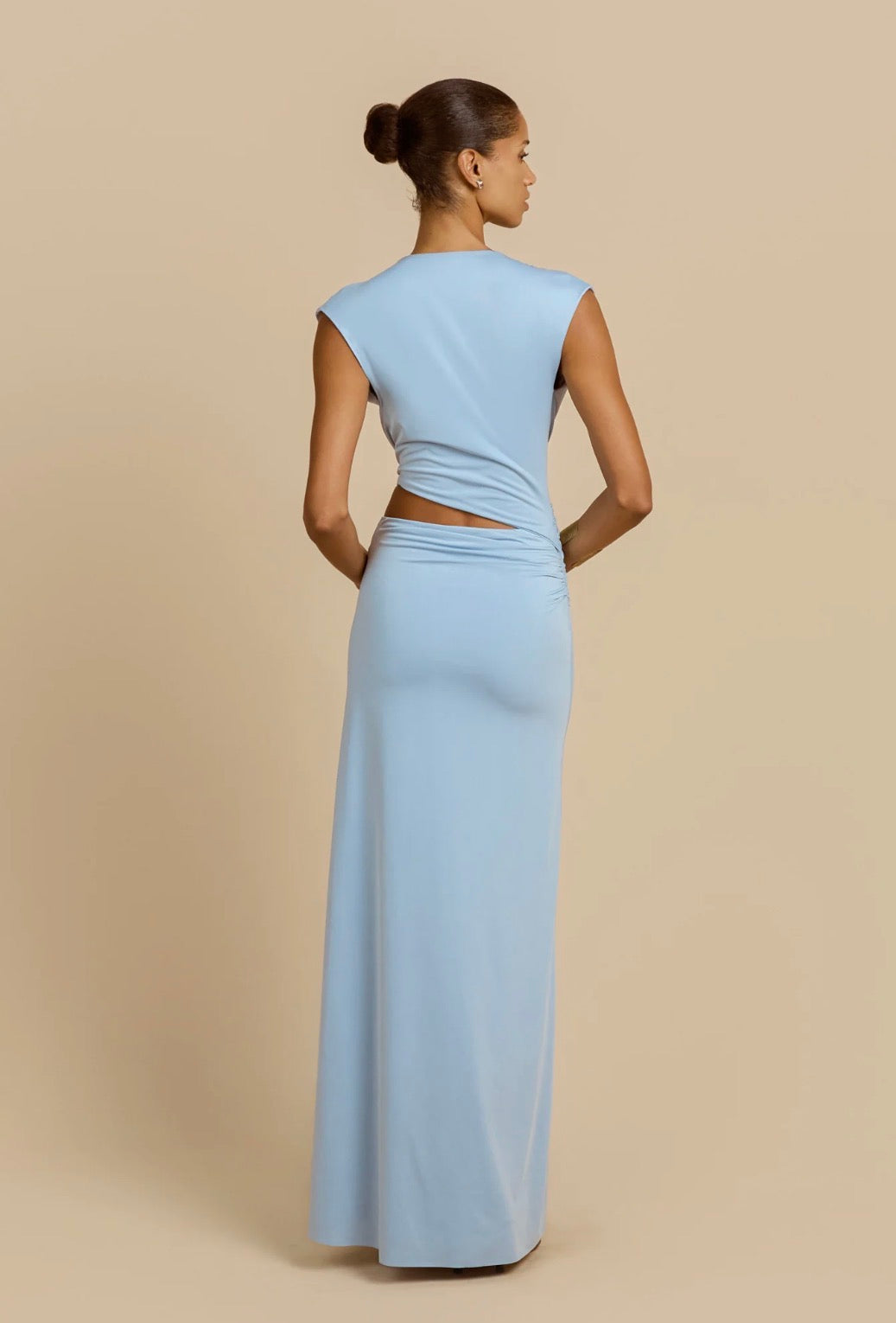 Woman wearing a light blue gown with cut-out design on a beige background