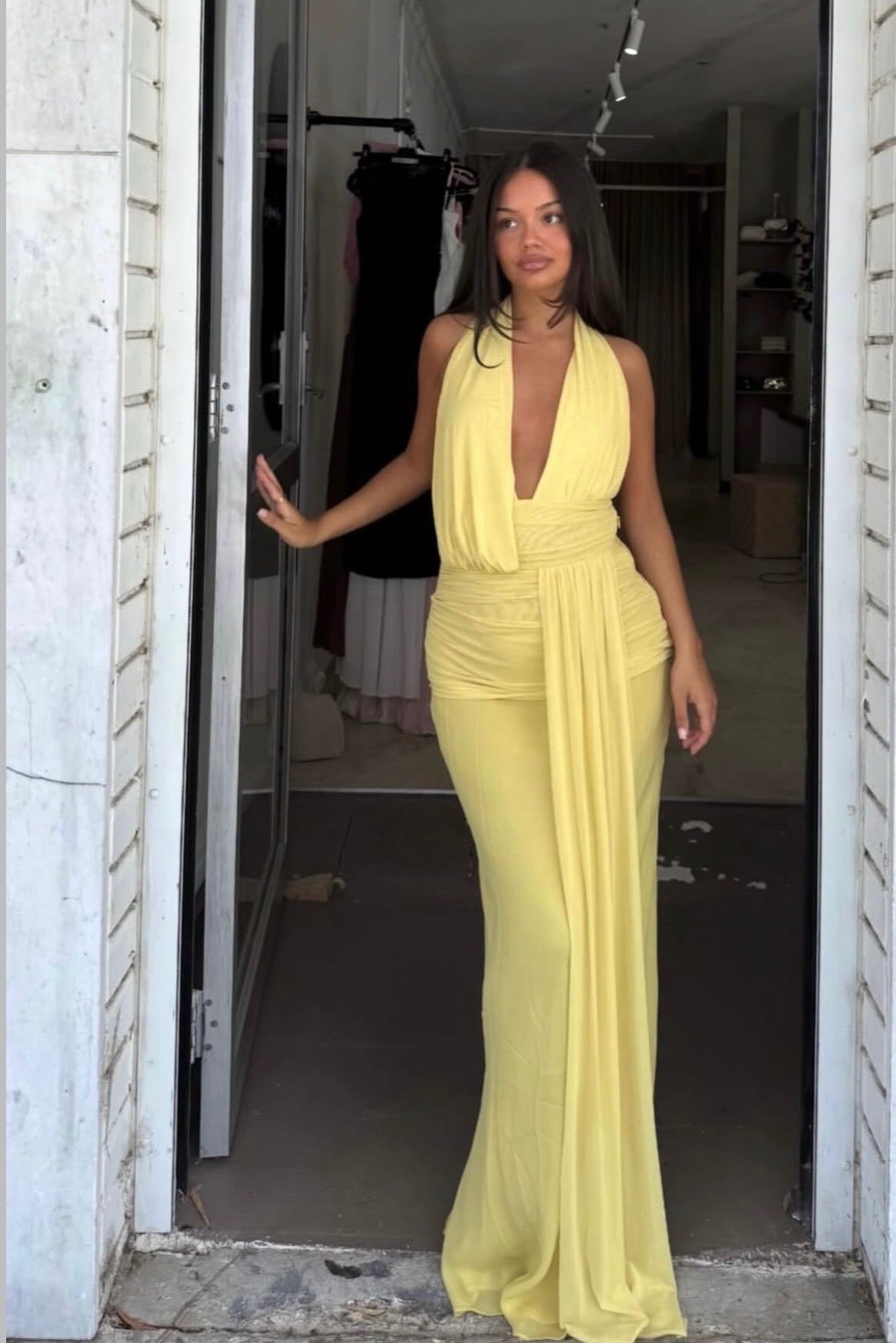 Woman wearing a yellow dress standing in a doorway.