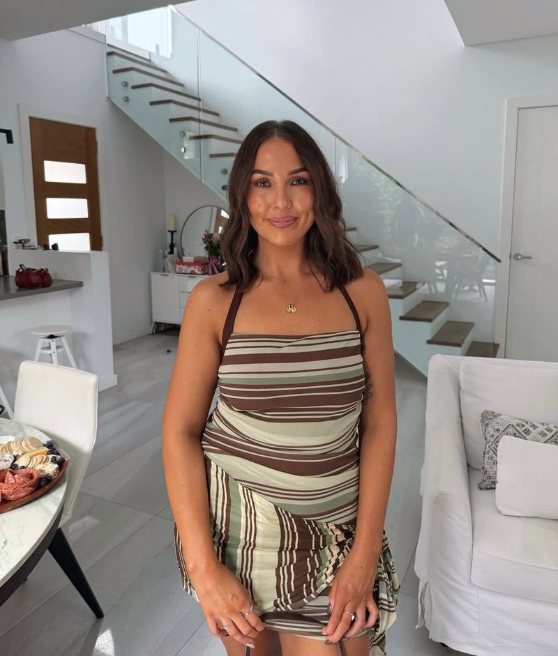 Woman in a striped dress standing in a modern living room. - @silviamitchellx