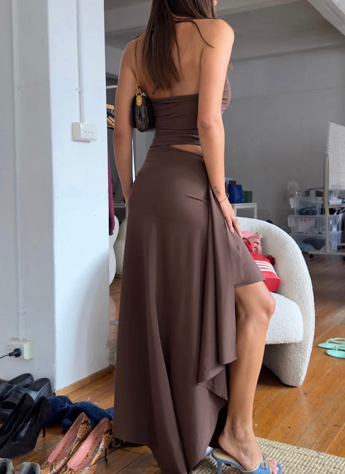 Woman wearing a brown dress with cut-out design in a room.