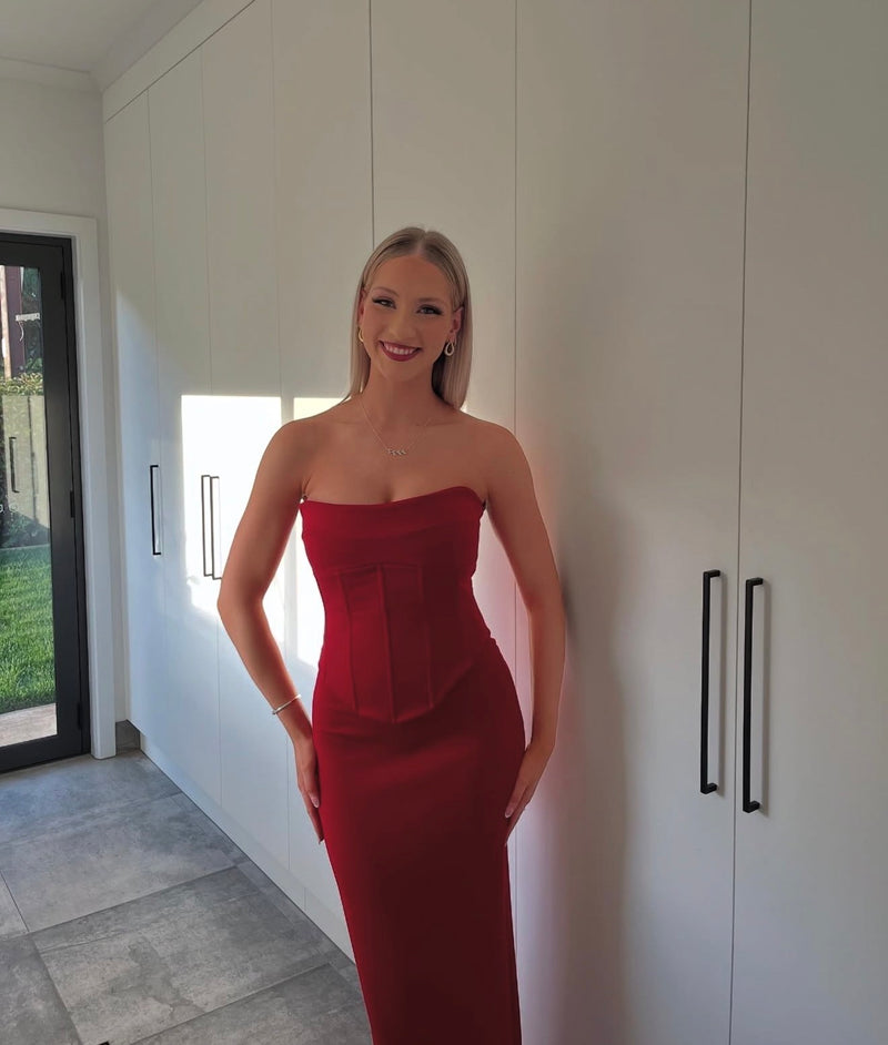 Woman in a red strapless dress standing in a modern interior setting. - @sskyemorrison