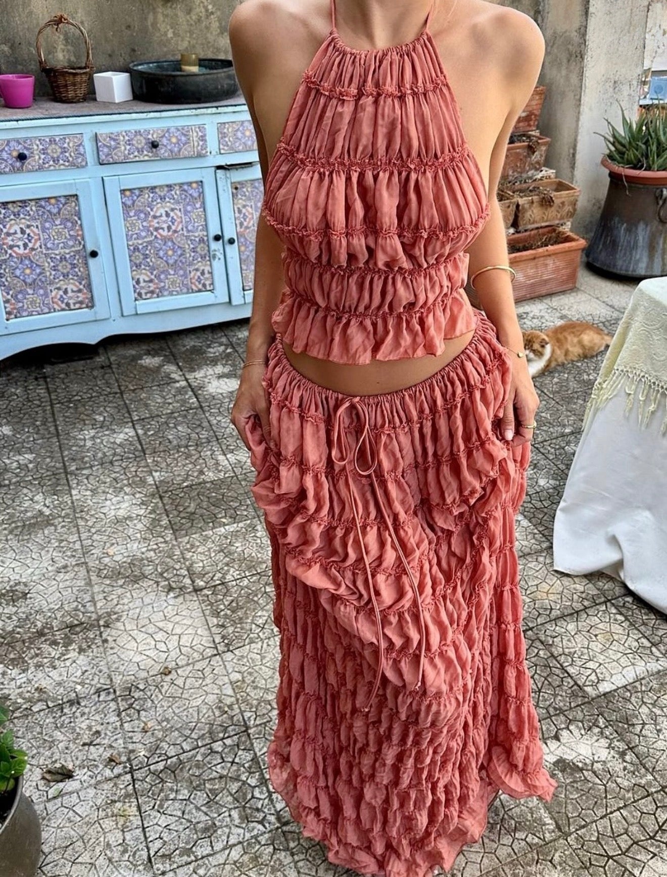 Person wearing a pink ruffled dress standing on a stone patio.