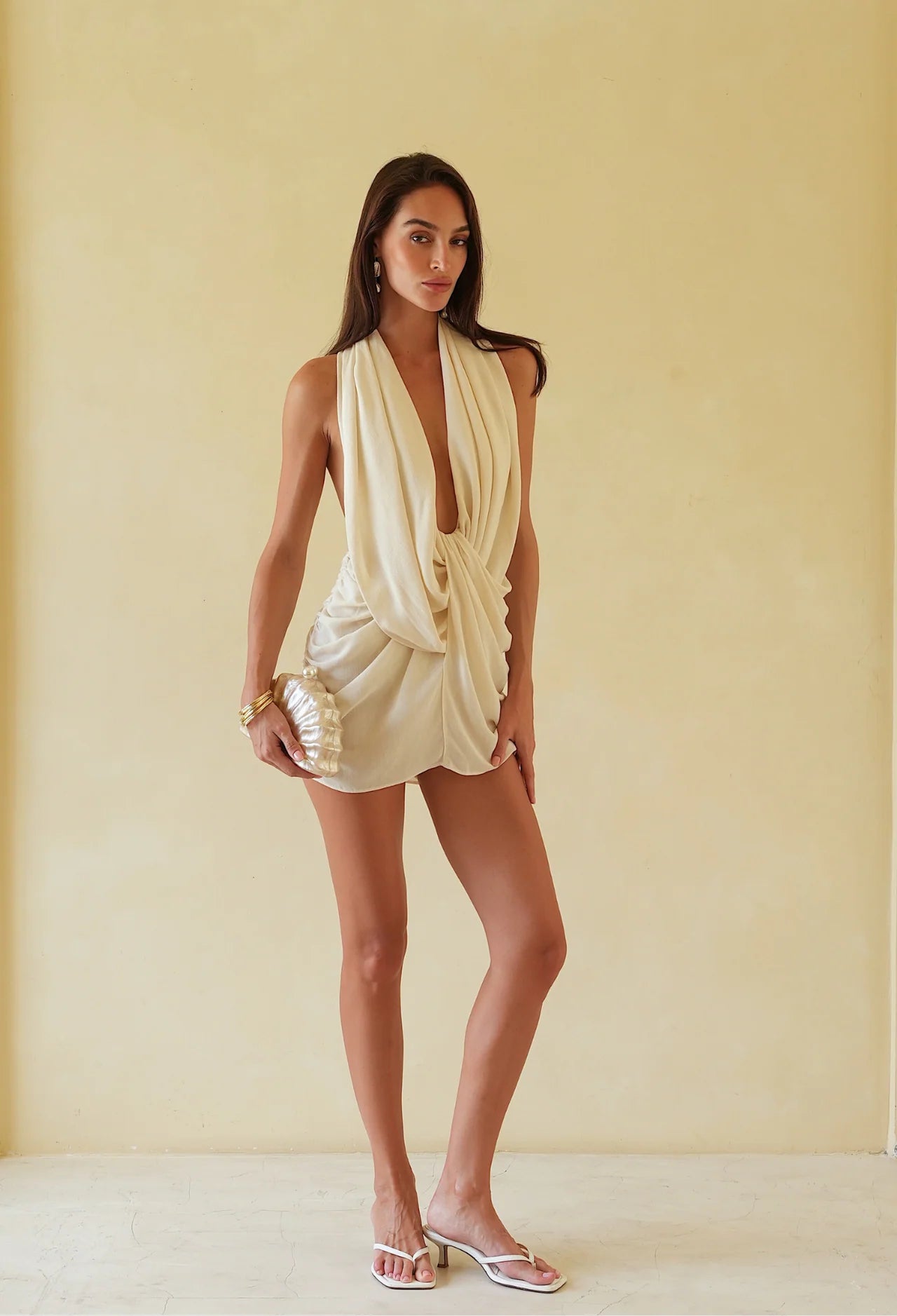 Woman wearing a cream-colored dress against a beige background