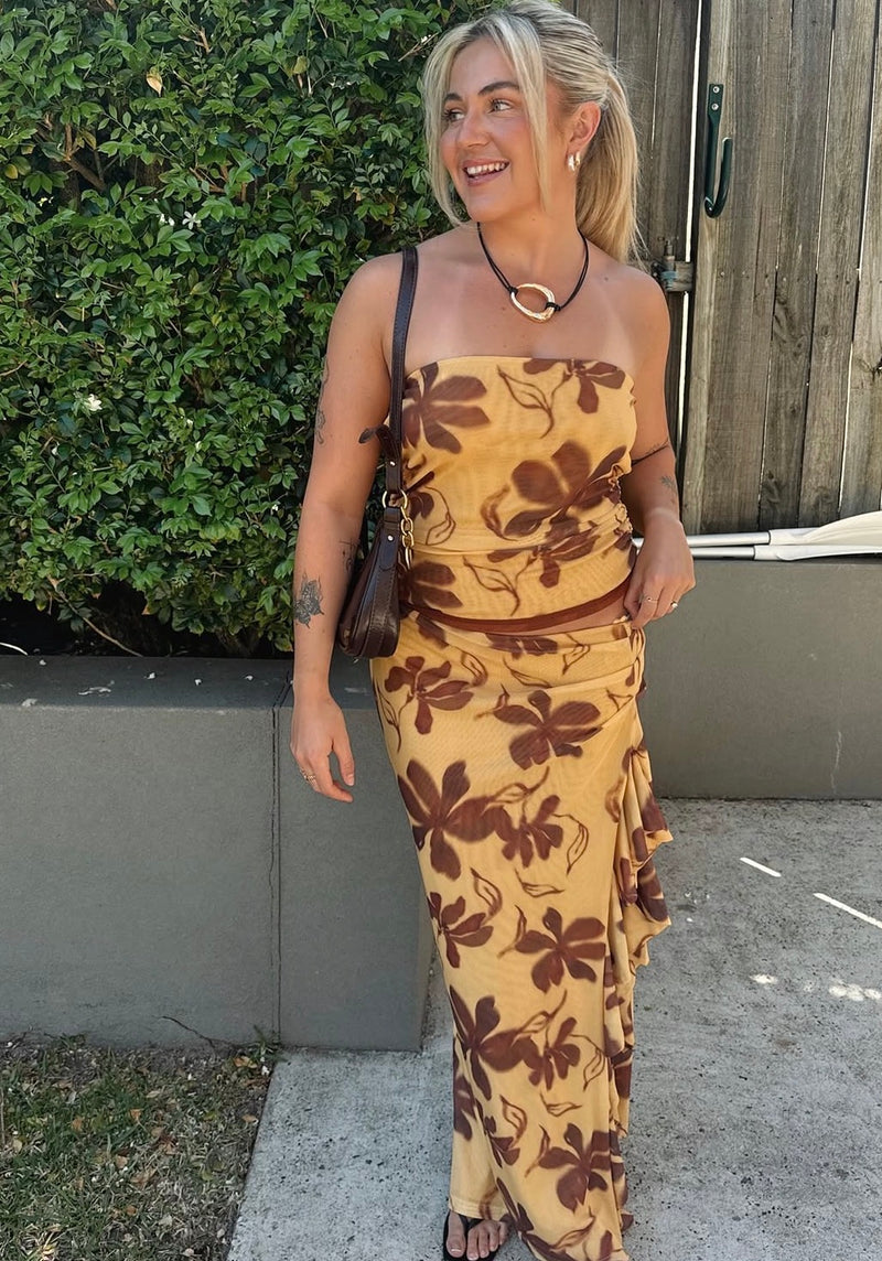 Woman wearing a floral dress standing outdoors next to a building. - @_jessfriend