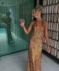 Woman in a floral dress holding a glass of wine indoors.