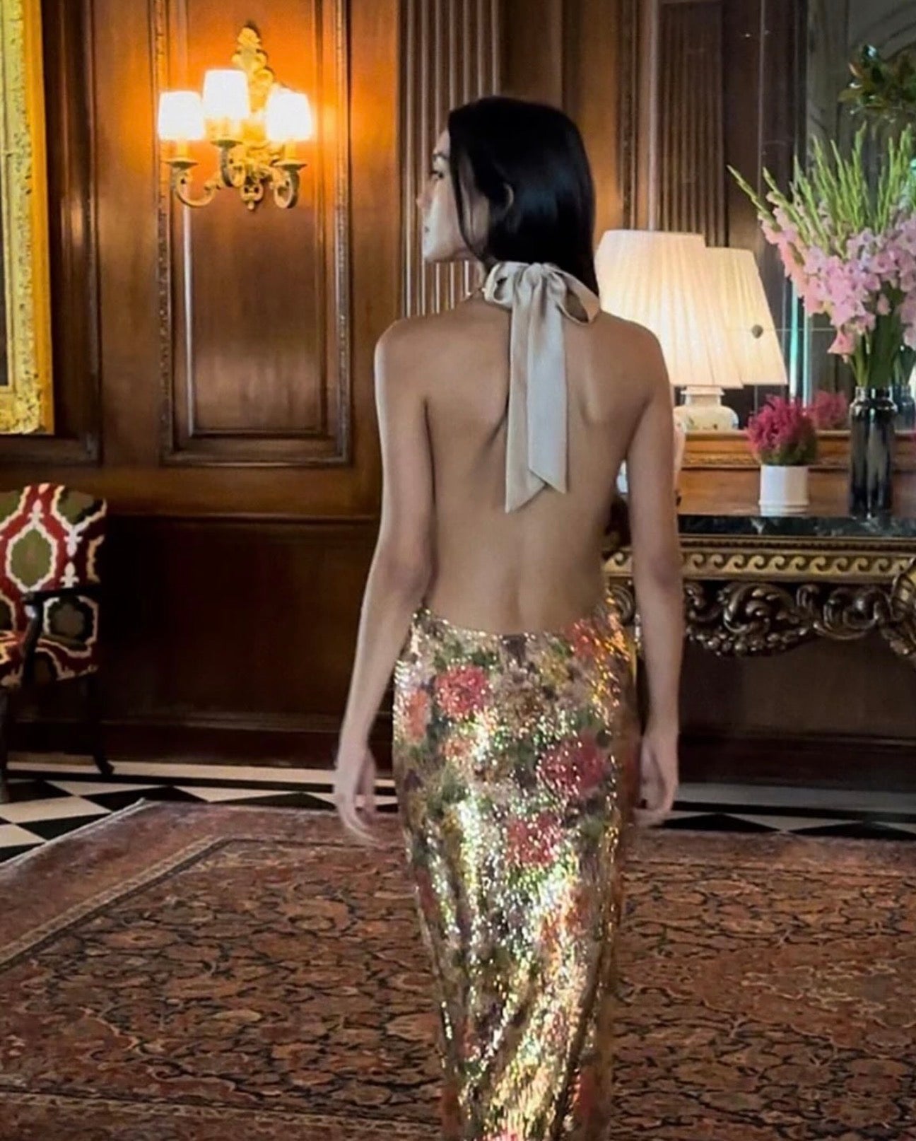 Woman in a floral dress with a bow at the back in an elegant room.